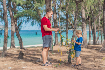 Camping people outdoor lifestyle tourists in summer forest near lazur sea. Blond boy son with...
