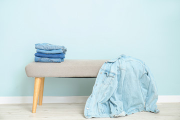 Bench with modern jeans clothes near color wall
