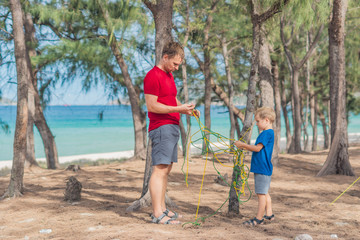 Camping people outdoor lifestyle tourists in summer forest near lazur sea. Blond boy son with...