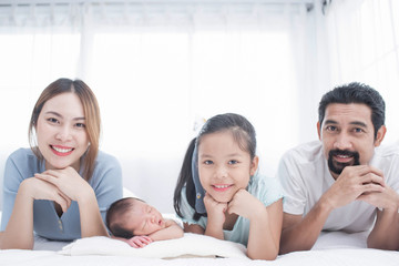 happy family mother, father and children laughing, playing and smiling in bed in bedroom at home. a young family with young children to bed in the bedroom.