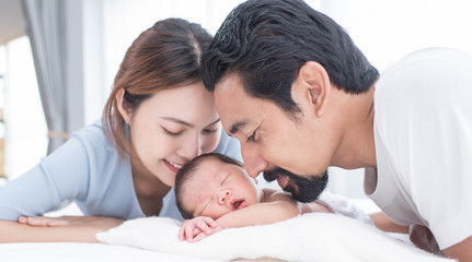 smiling mother and father holding their newborn baby at home..portrait of happy family at home, young parents holding on hands little sweet newborn baby, love and happiness concept.