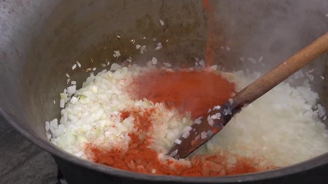 Onion and pepper mixing in a kette on free fire.