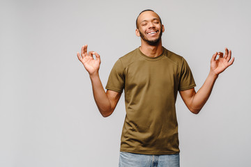 Stress relief techniques concept - happy young african-american man meditating with eyes closed over grey background