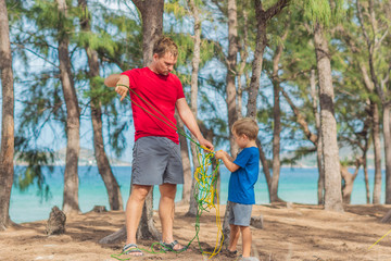 Camping people outdoor lifestyle tourists in summer forest near lazur sea. Blond boy son with...