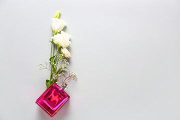 Bottle of floral perfume on light background