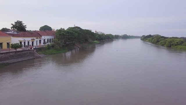 Santa Cruz de Mompox in Colombia. Aerial Drone fly over the Magdalena River, rising up to reveal the historic town centre.	