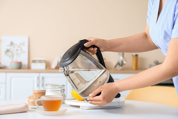 Fototapeta na wymiar Woman with electric kettle brewing tea in kitchen