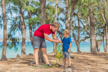 Camping people outdoor lifestyle tourists in summer forest near lazur sea. Blond boy son with...