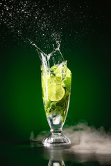 Glass of fresh mojito with splash on dark background
