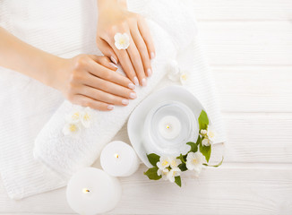 Obraz na płótnie Canvas beautiful french manicure with jasmine, candle and towel on the white wooden table. spa