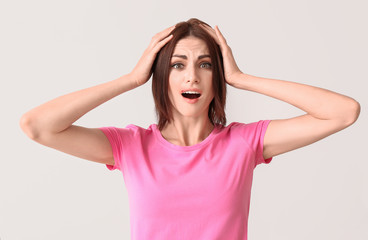 Stressed young woman with cold sore on light background