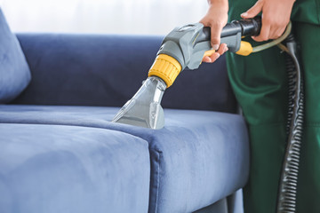 Dry cleaner's employee removing dirt from sofa in house