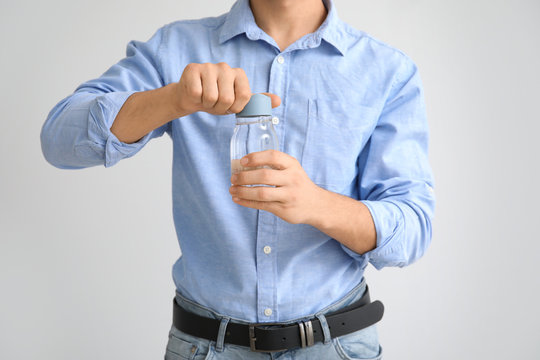 Young Man With Bottle Of Water On Light Background