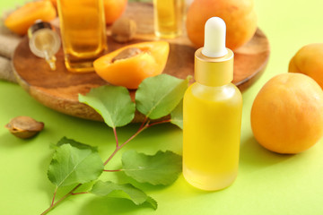 Bottle of apricot essential oil on color background
