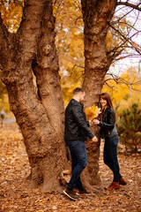 man and a woman standing near tree in autumn Park.