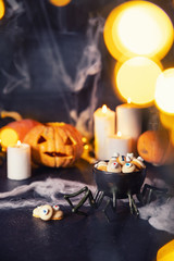 Stylized halloween sweet candies and cookies for holiday on dark background with cobwebs, pumpkins and candles