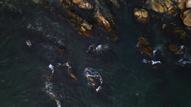 Aerial still of coastal waves crashing on rocks