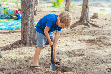 Camping people outdoor lifestyle tourists, summer forest near lazur sea. Blond boy play study...