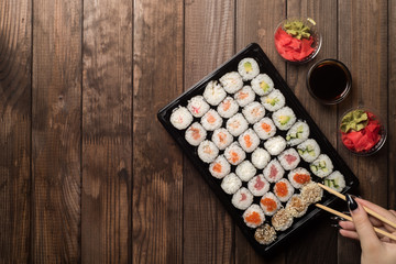 The hand with chopsticks picks up the sushi rolls. Traditional Asian cooking concept.