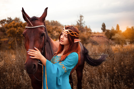 Beautiful young female elf with long dark wavy hair petting her horse resting in the woods forest nymph stroking her horse care pet love animals harmony caring owner gentle creature myth
