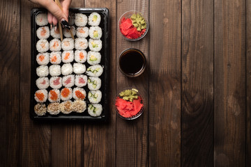 The hand with chopsticks picks up the sushi rolls. Traditional Asian cooking concept.