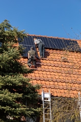 Fototapeta premium Workers installing solar electric panels on a house roof in Ochojno. Poland