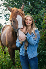 Young smiling blonde with her horse looking at camera