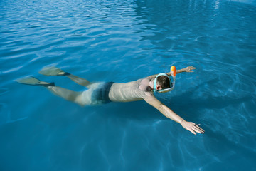 a guy in a snorkeling mask and fins floats on the surface of the water