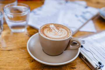 selective focus coffee flatwhite with latte art, on wooden table, with  blurred menu in background copy space