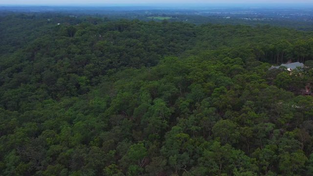 Aerial crane shot of an epic scene of rural Sydney Australia, Houses and green tree dense hilly forest on a clear day.