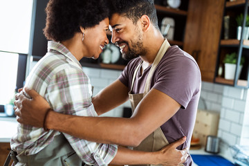 Beautiful couple are hugging and smiling while spending time in kitchen