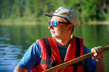 A portrait of a guy who is dressed in a life jacket with glasses and a cap on the background of the...