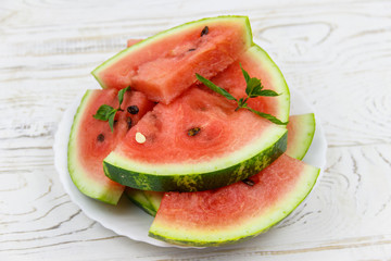 Fresh ripe sliced watermelon in white plate on a white wooden table