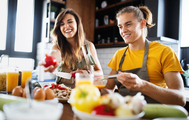 Beautiful couple is smiling while cooking together in the kitchen