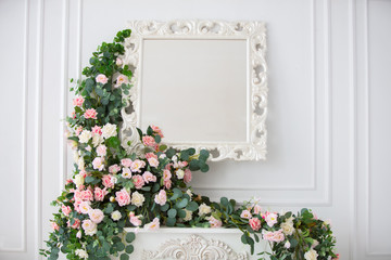 Mirror on a white wall, decorated with flower garlands.