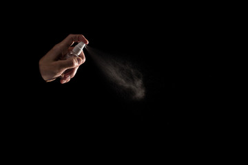Male hand spraying antiseptic against virus isolated on black background
