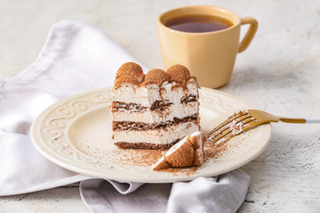 Plate with tasty tiramisu and tea on table