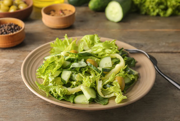 Plate with tasty cucumber salad on table