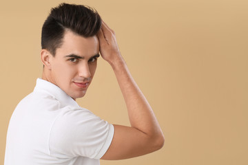 Handsome man with stylish hairdo on color background