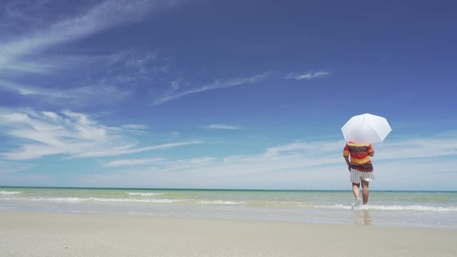 Asian traveler walking on beach with turquoise blue sea background