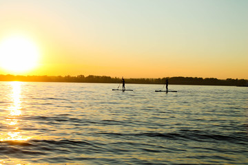Fototapeta na wymiar Stand-up surfing. Classes on the river at sunset.
