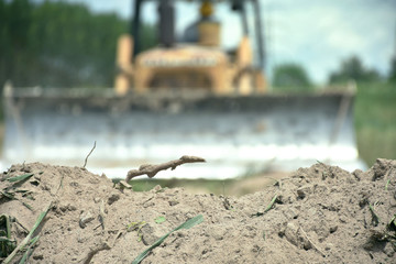 A pile of soil isolated with blurred image of tractor working in a field