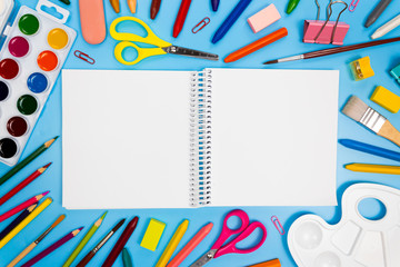 Sketchbook mockup white paper with art supplies. Back to school design. Many art and craft tools for kids. Open notepad blank sheets mock up. Colorful pens, pencils, paints, crayons around the album.