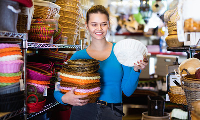 Cheerful positive female teenager and assortment of wicker basket in decor store