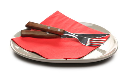 Porcelain plate, cutlery (knife and fork) with red serviette, napkin isolated on white background