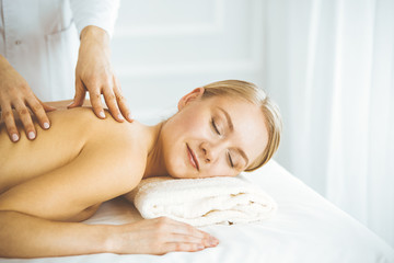 Obraz na płótnie Canvas Beautiful happy woman enjoying back massage with closed eyes. Beauty and Spa salon concept