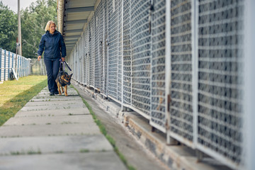 Female officer with security dog walking by locked cages