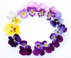 Fototapeta na wymiar Round Frame with flowers and leaves. Top view background with pansy flowers. Flowers composition. Mock up with plants. Flat lay with flowers on white table. Woman day concept. Copyspace for text.