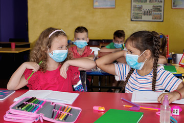 Protection during the pandemic. Two little children  with medical mask.Greetings at school