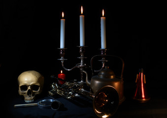 A skull, a magnifying glass, a trumped, a brass candle stick with 3 white candles, a trumpet mute...